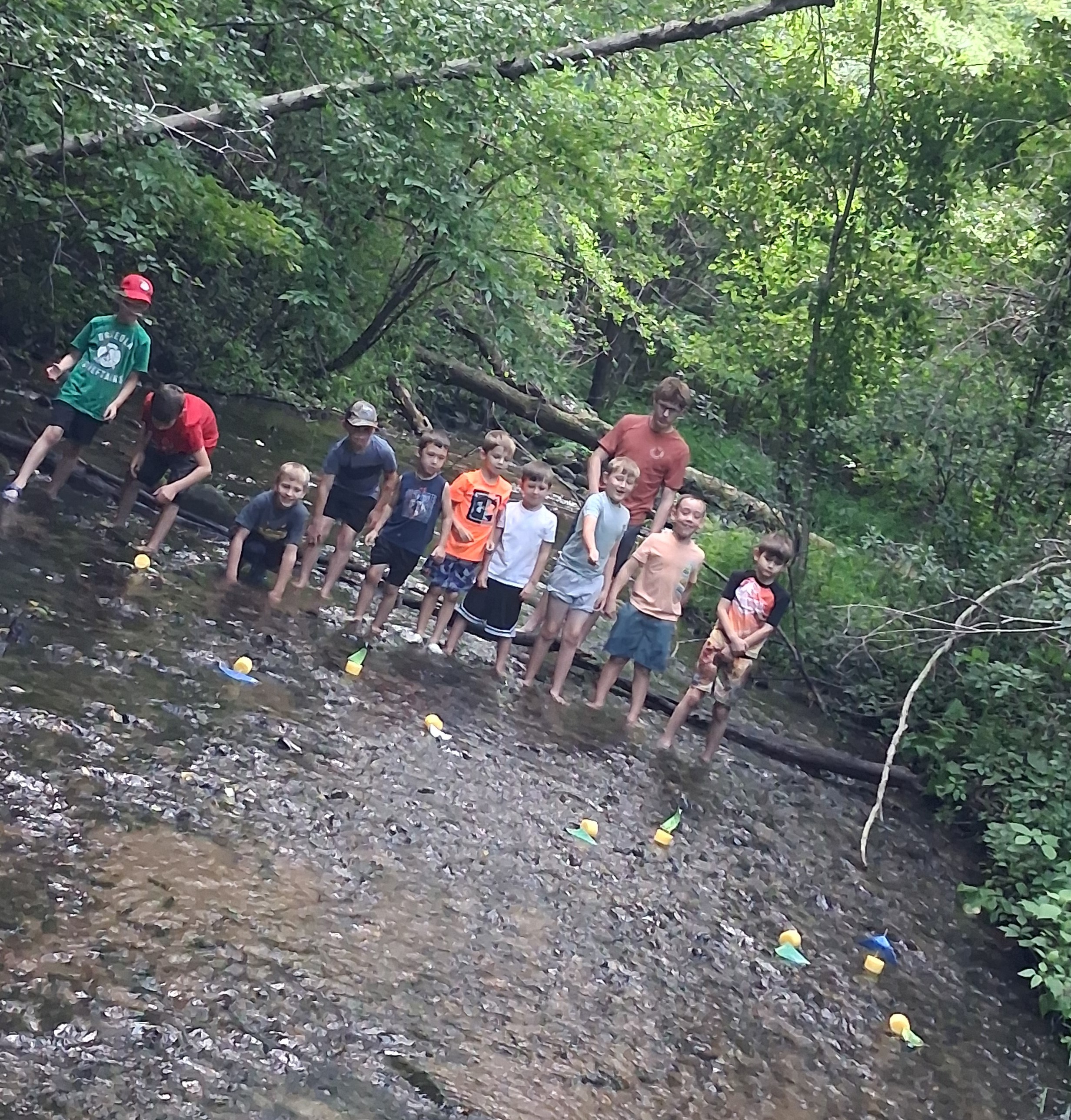 Students racing boats in a creek.